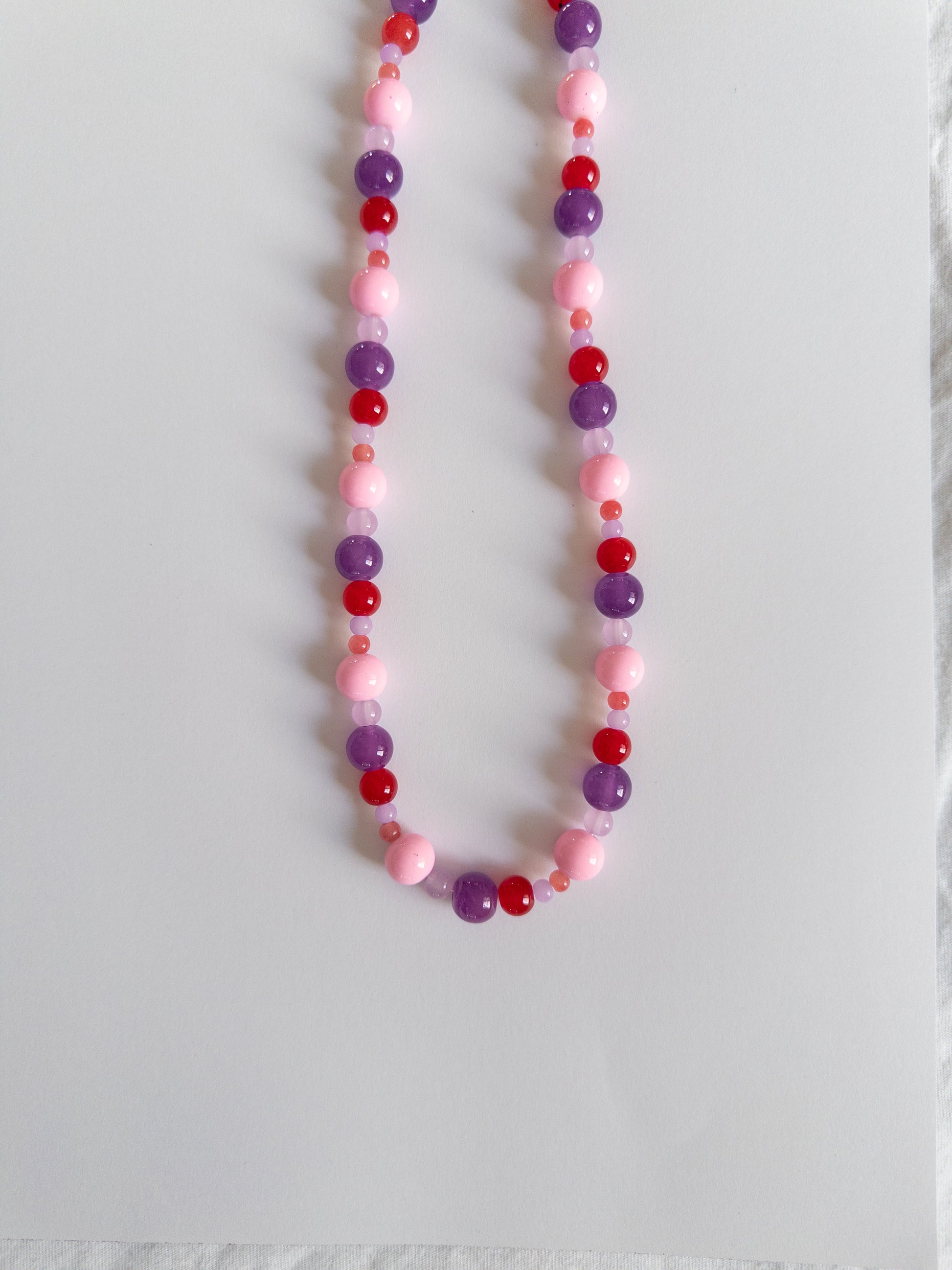 Berry coloured beaded necklace on white background