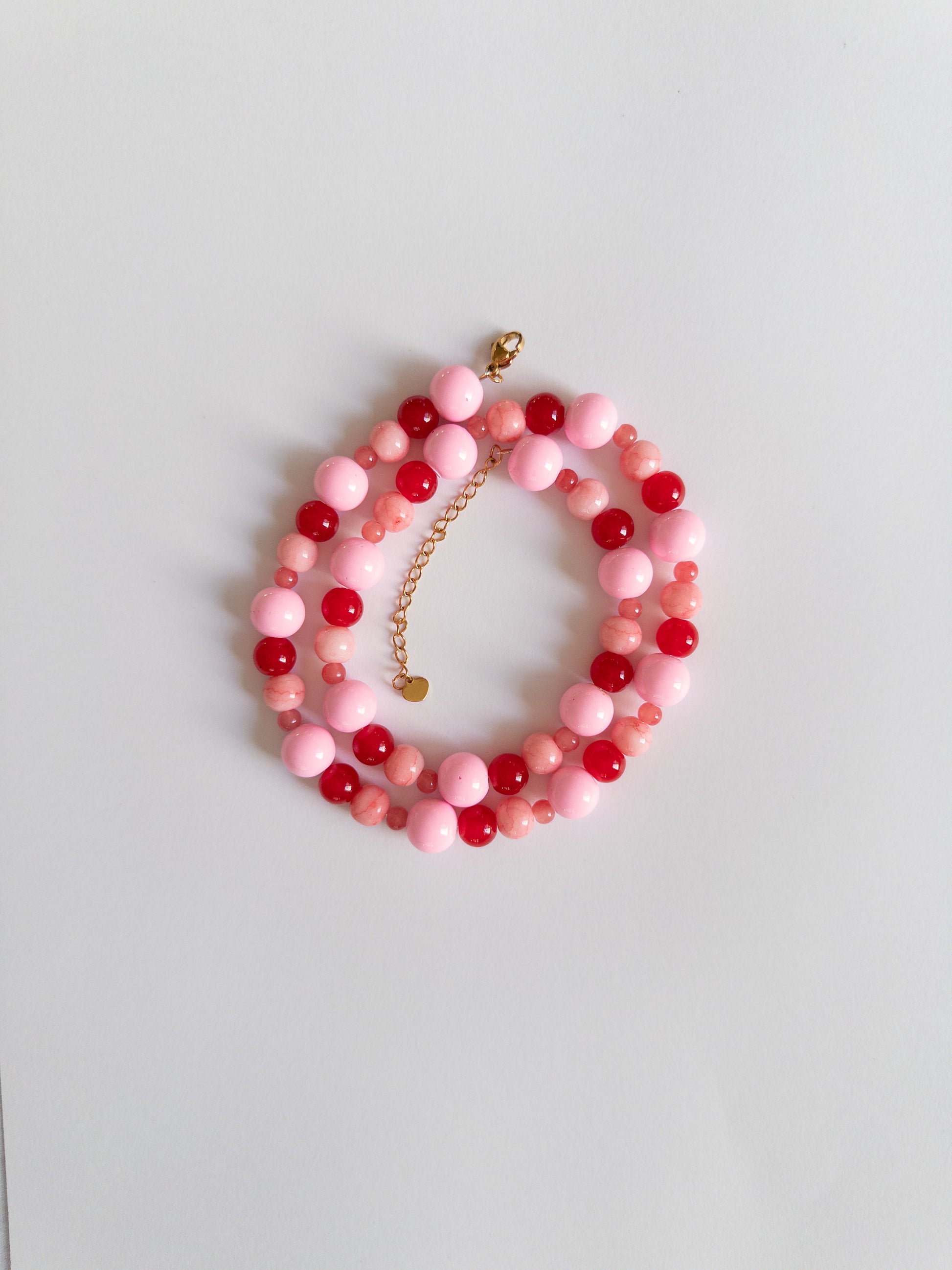 Red and Pink chunky beaded necklace styled on a white background