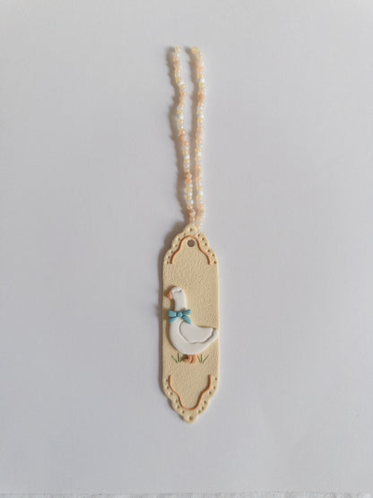 Beige coloured polymer clay bookmark with a white goose on it and a beige and white beaded tassel