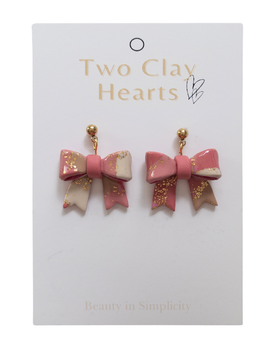 Terracotta coloured bow-shaped earrings on a 'Two Clay Hearts' branded card.