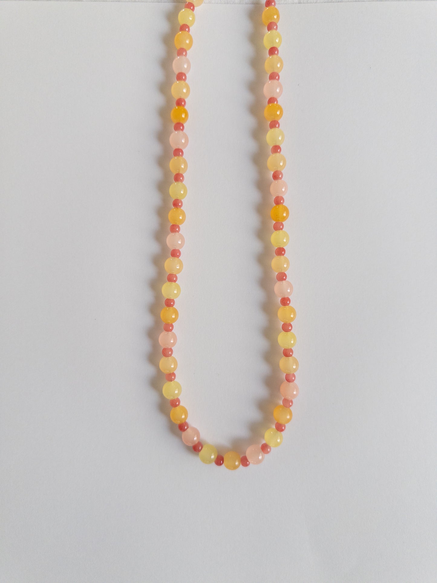 Orange, yellow and pink beaded necklace on a white background