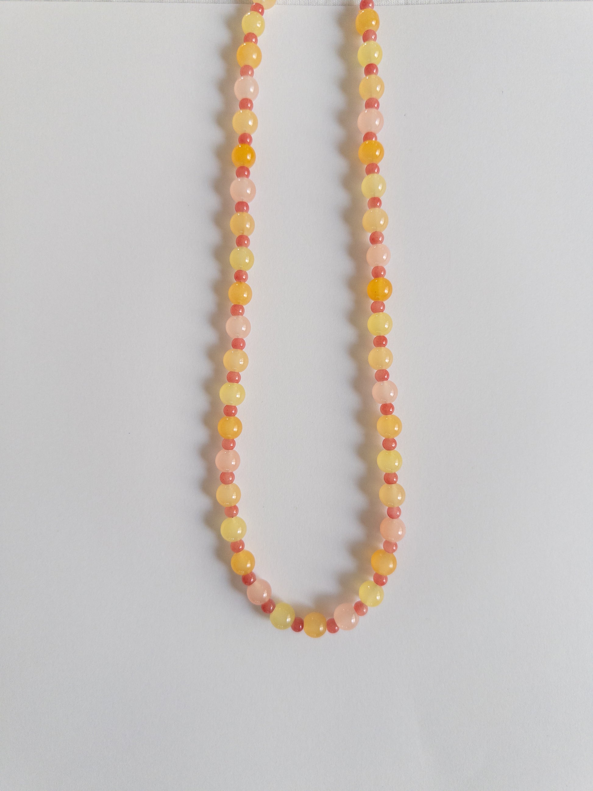 Orange, yellow and pink beaded necklace on a white background