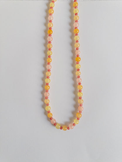 Orange, yellow and pink beaded necklace on a white background