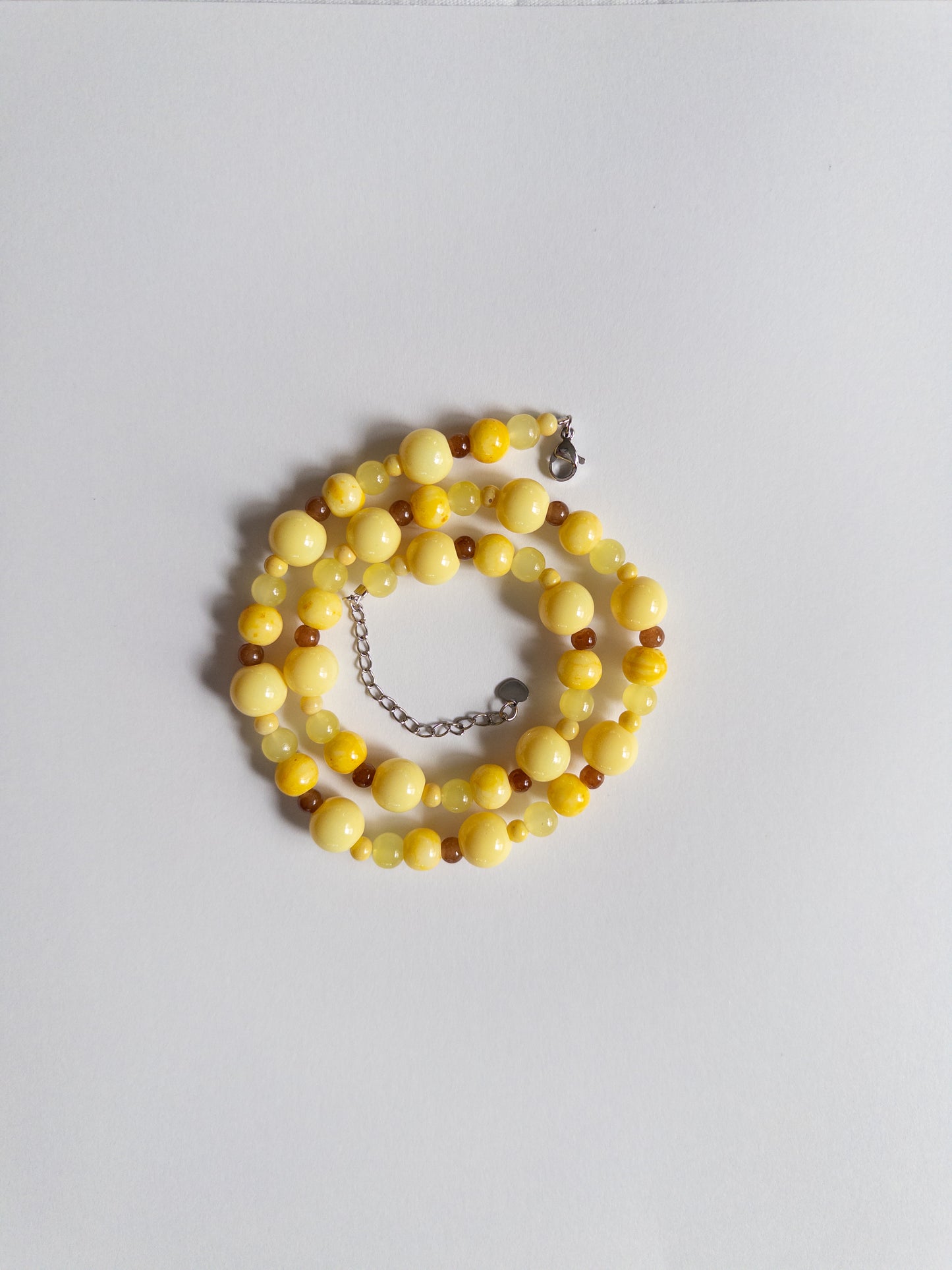 Yellow and brown beaded necklace styled on white background