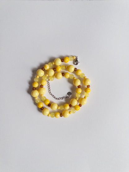 Yellow and brown beaded necklace styled on white background