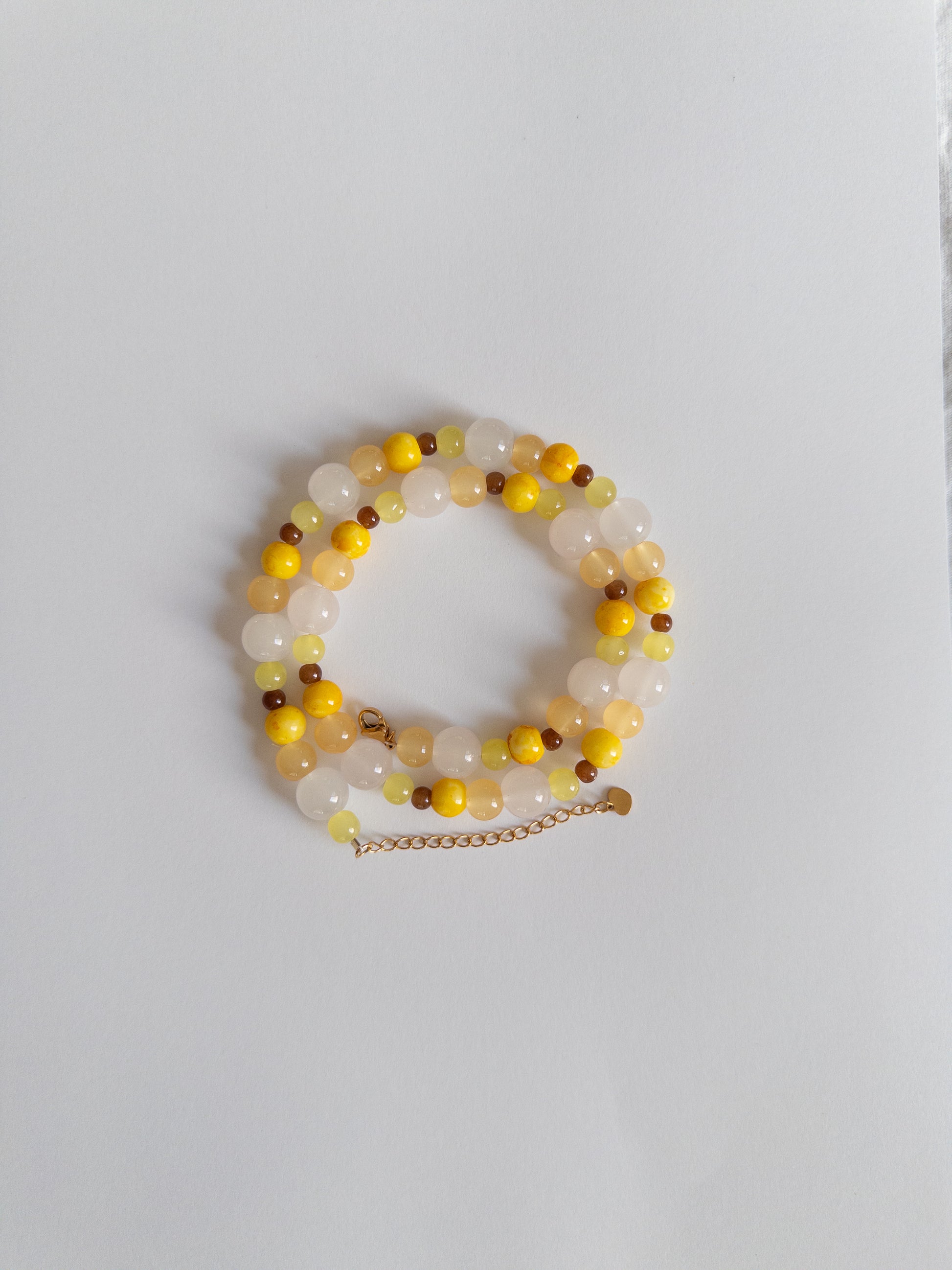 Yellow, brown and clear beaded necklace styled on white background