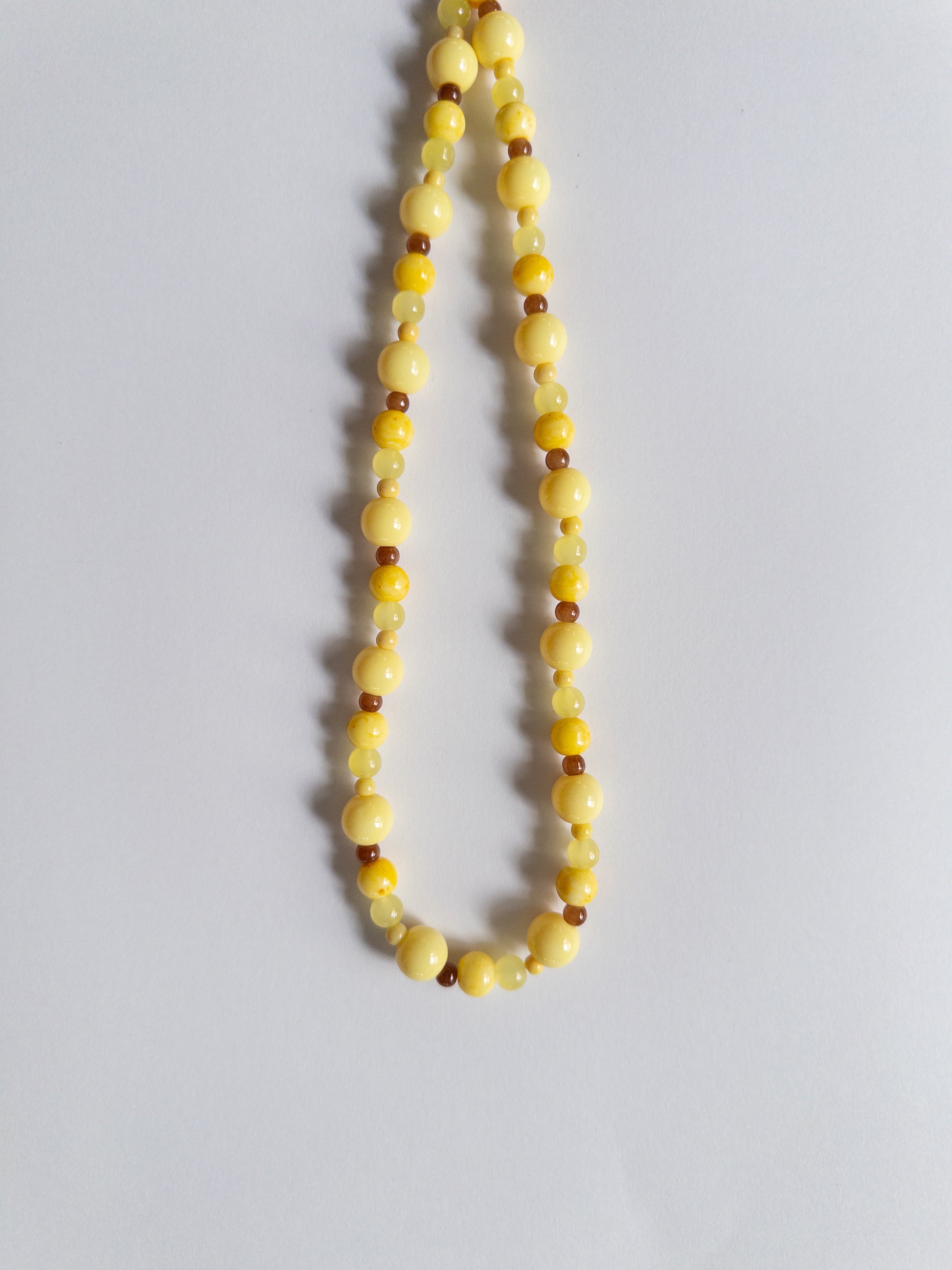 Yellow and brown beaded necklace on white background