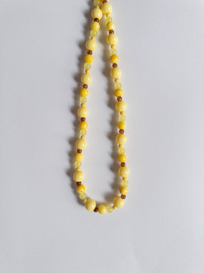 Yellow and brown beaded necklace on white background
