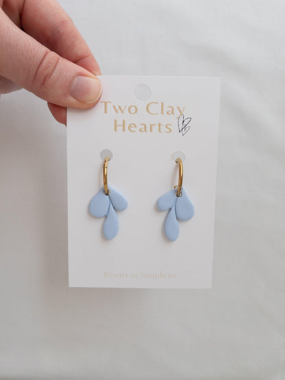 Elegant gold and blue leaf hoop earrings on white backing card