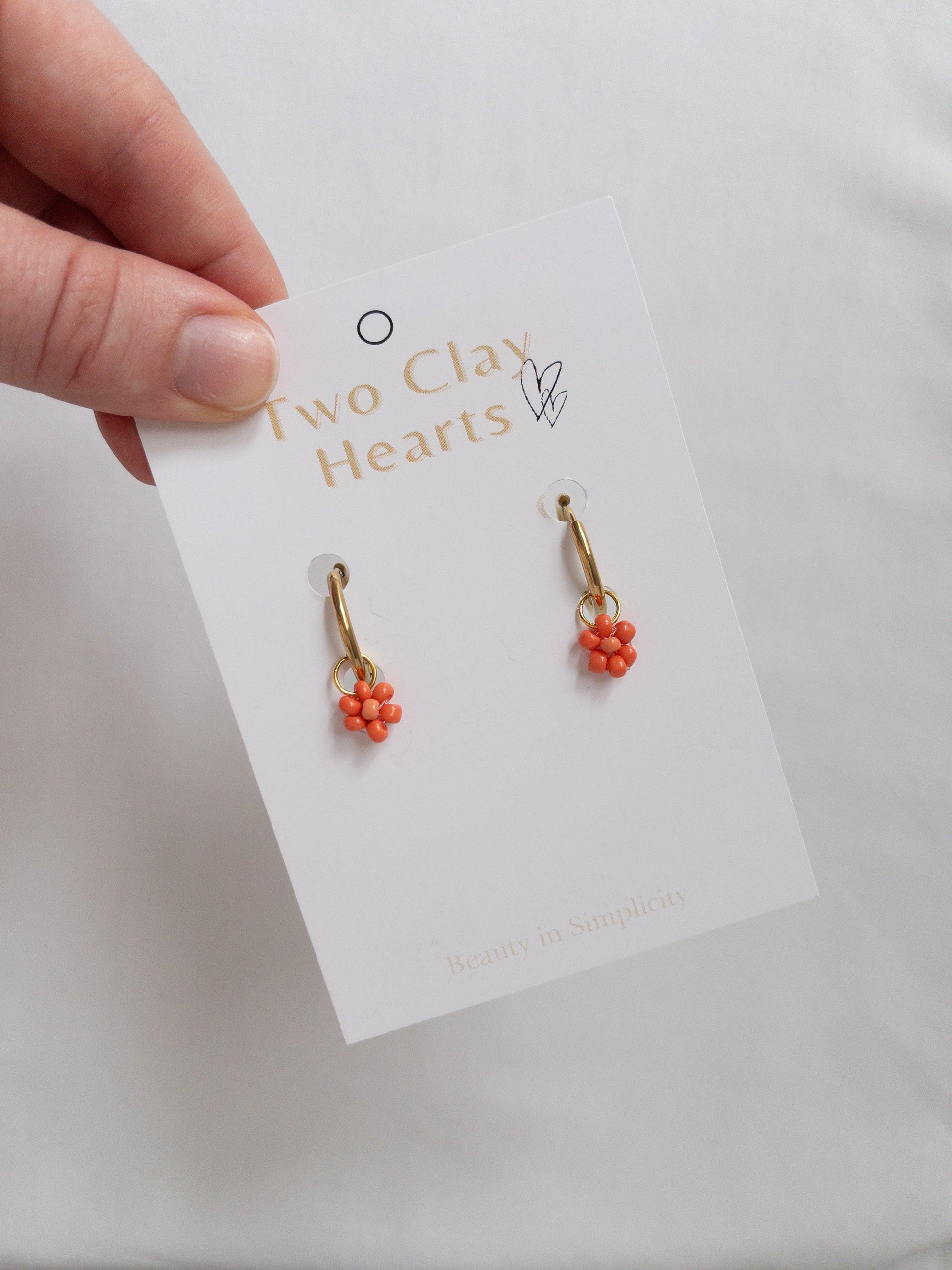 Gold hoops with coral beaded flowers on white backing card