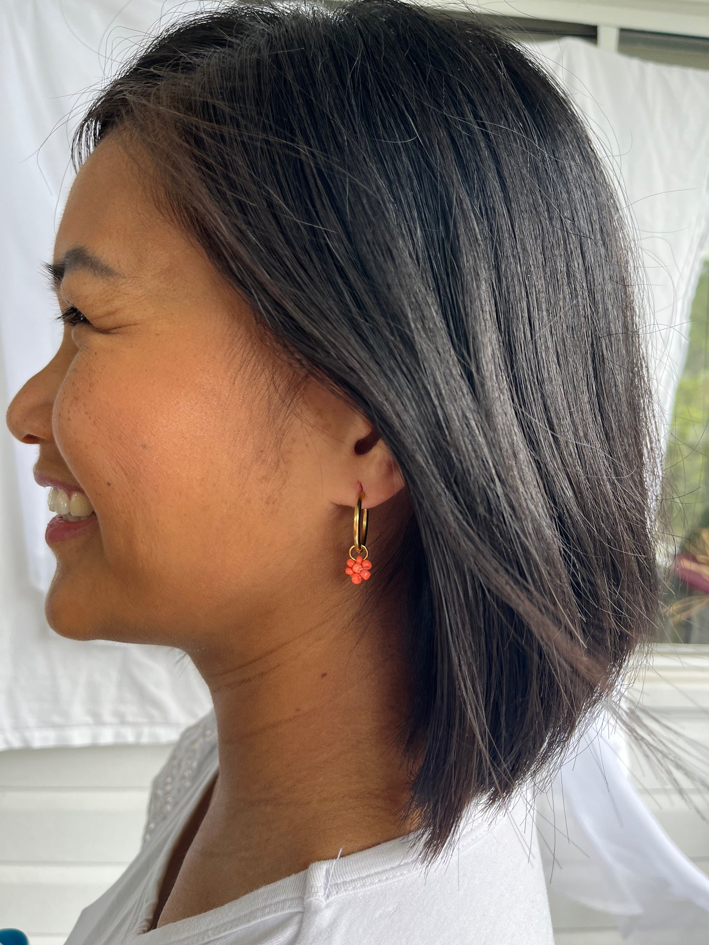 Gold hoops with coral beaded flowers on models ear