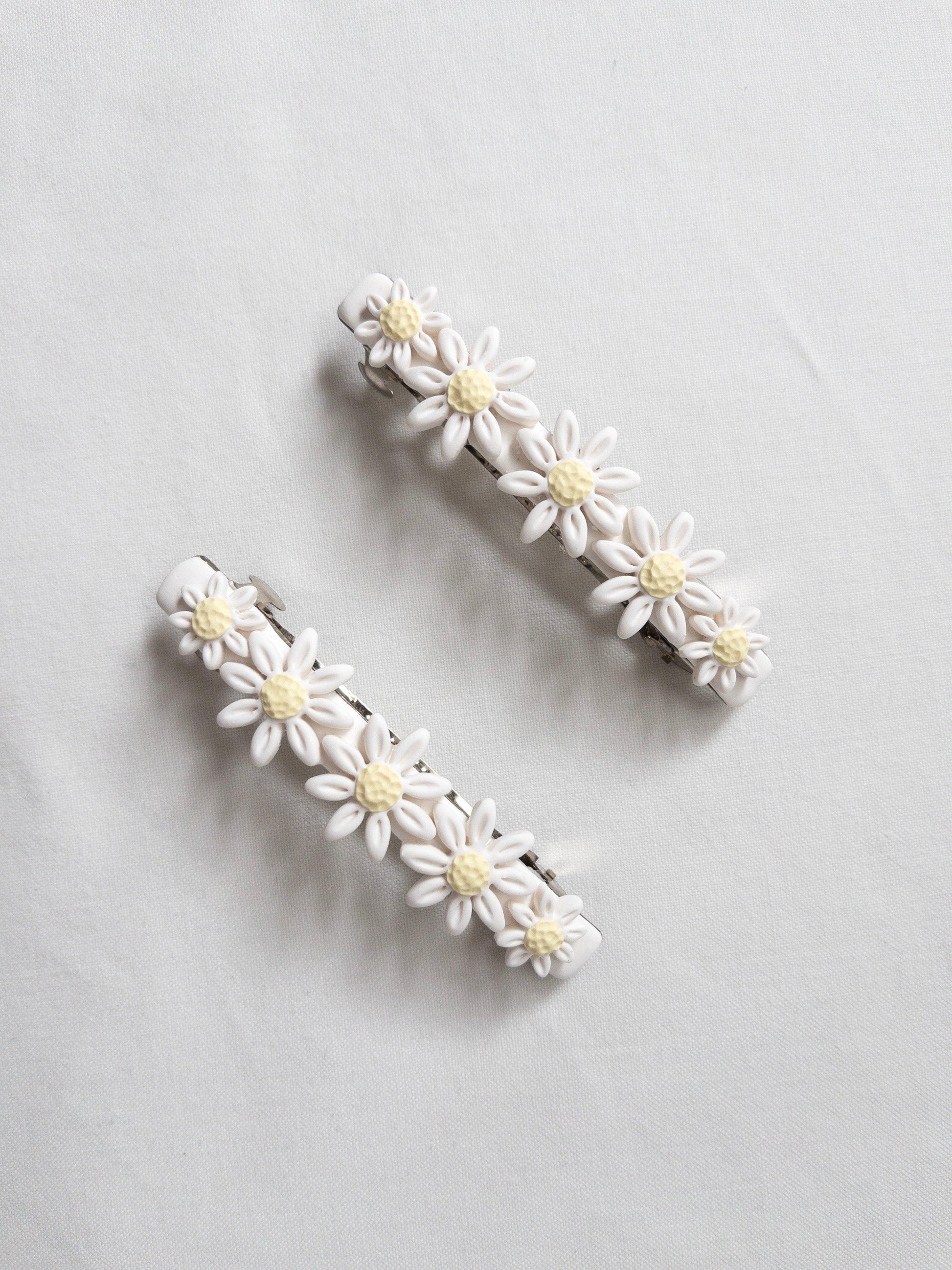 White, polymer clay flower hair barrettes on white backdrop