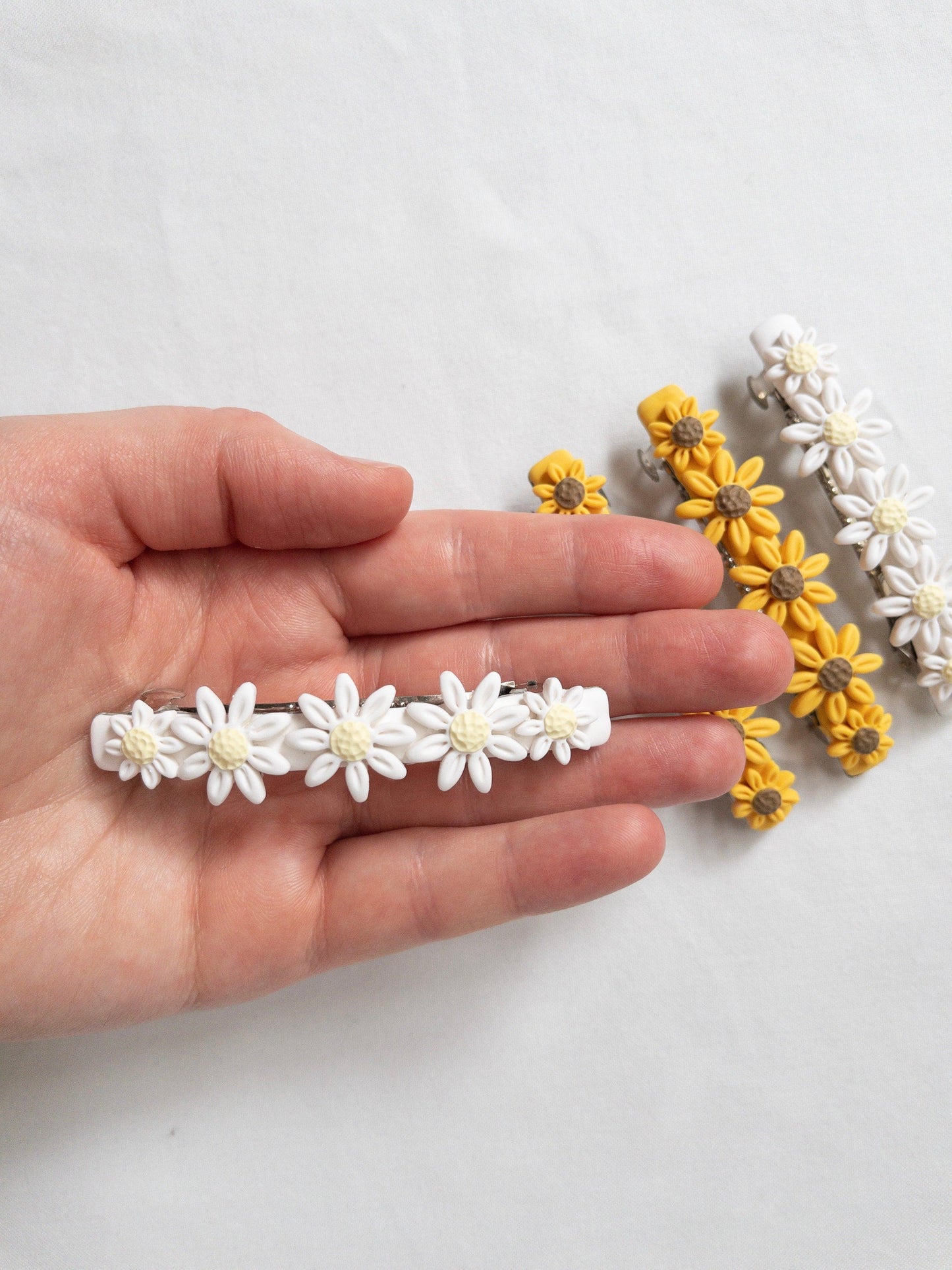 White, polymer clay flower hair barrette in models' hand