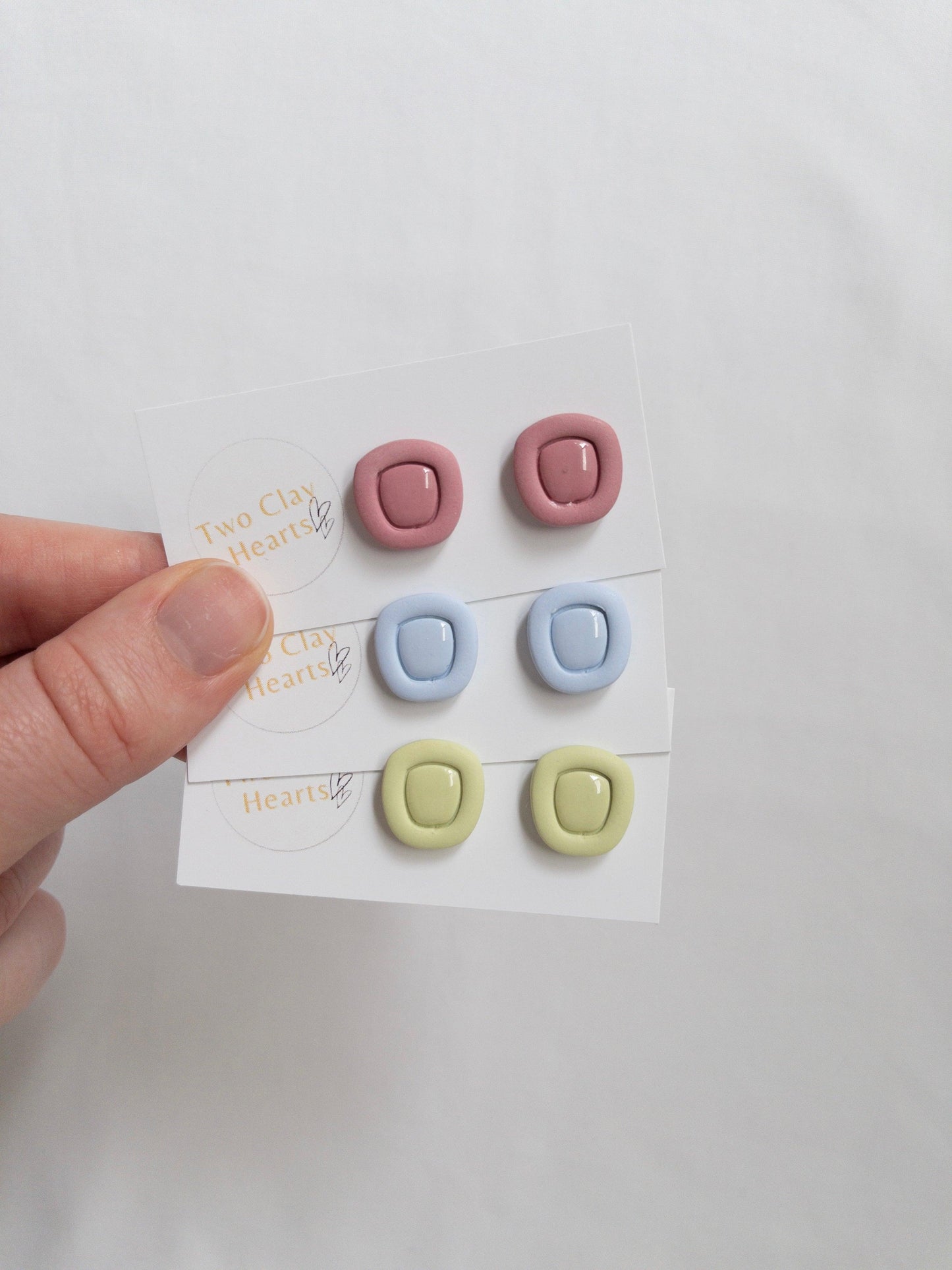 Polymer clay stud earrings with a resin centre, on white backing cards.