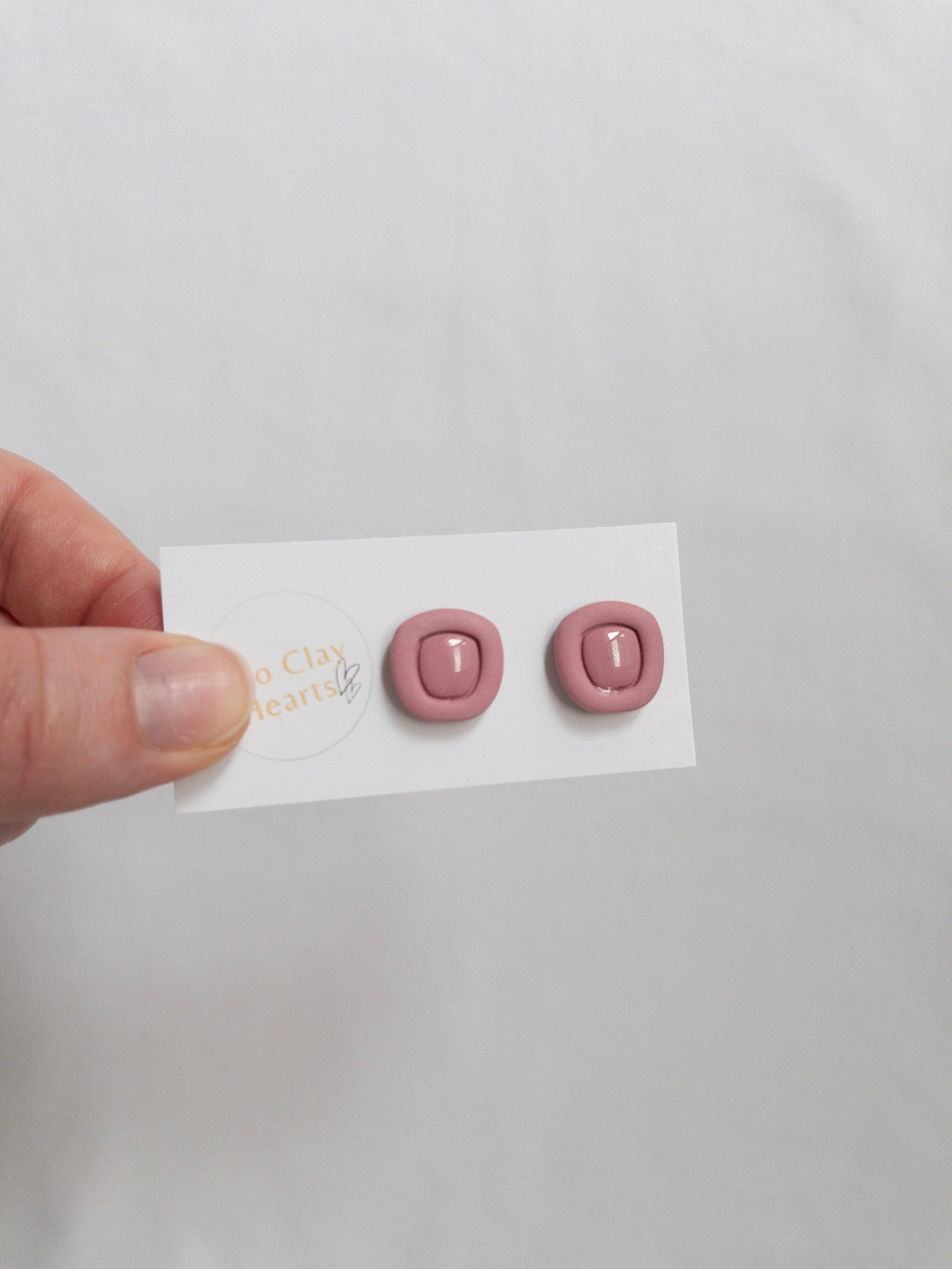 Maroon polymer clay stud earrings with a resin centre, on a white backing card