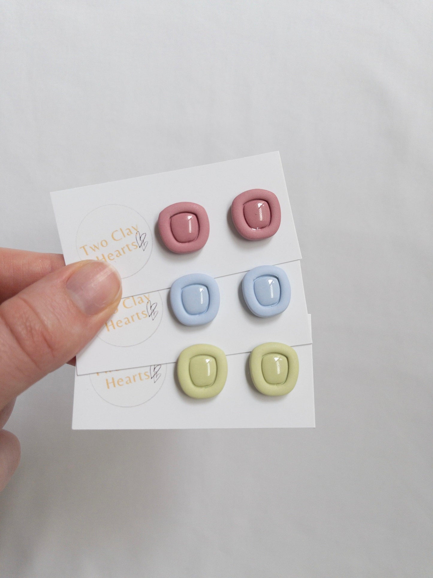 Polymer clay stud earrings with a resin centre, on white backing cards.