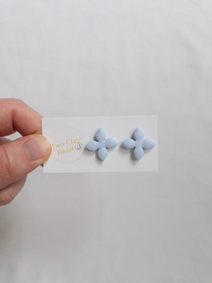 Blue, four petalled flower stud earring on backing card