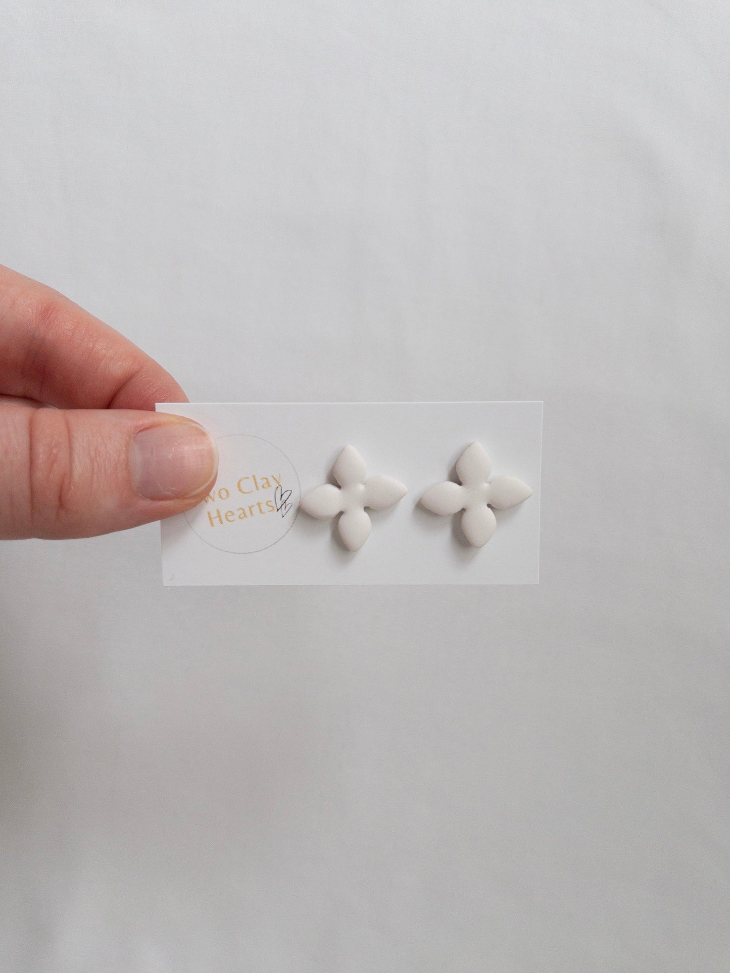 White, four petalled flower stud earring on backing card