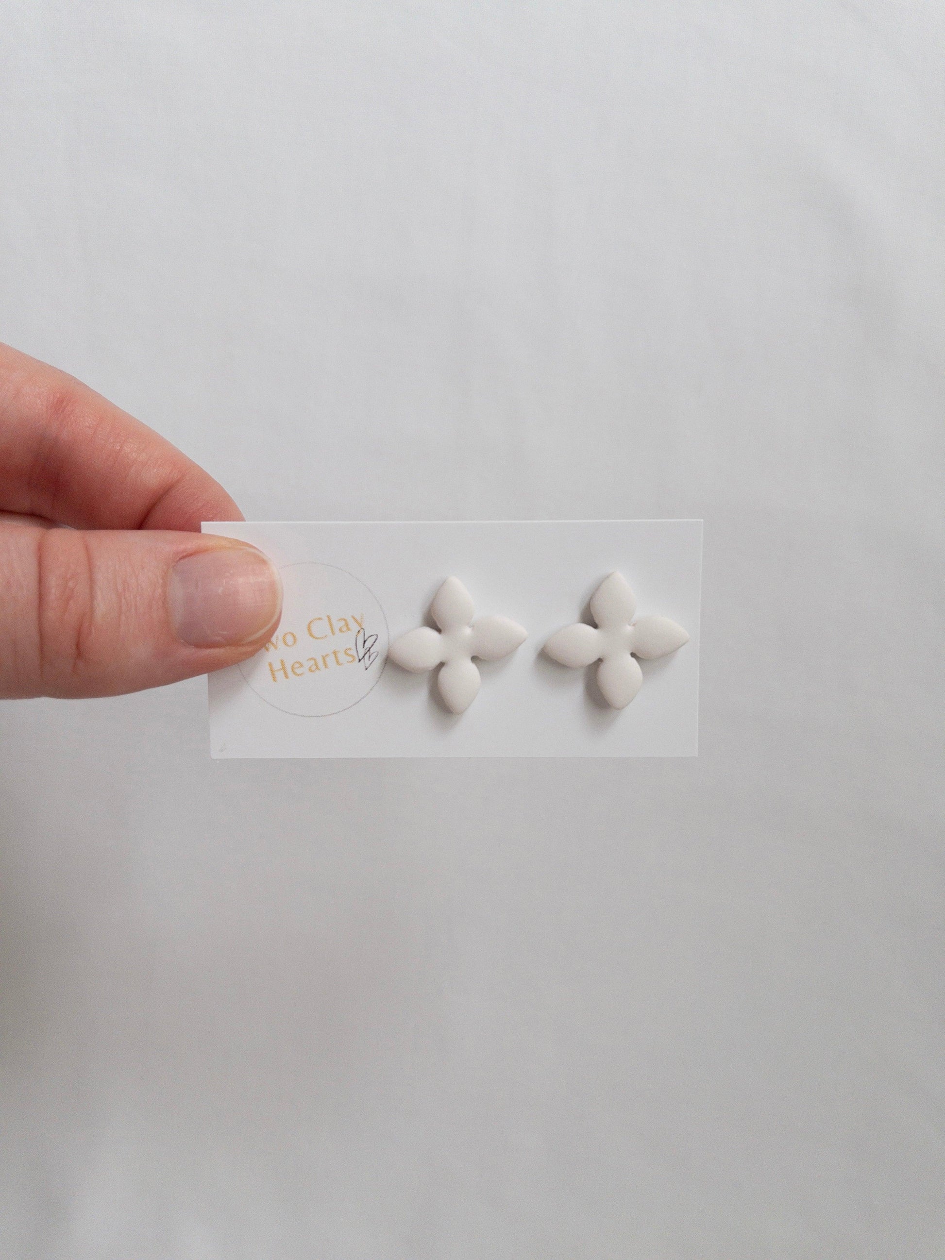 White, four petalled flower stud earring on backing card