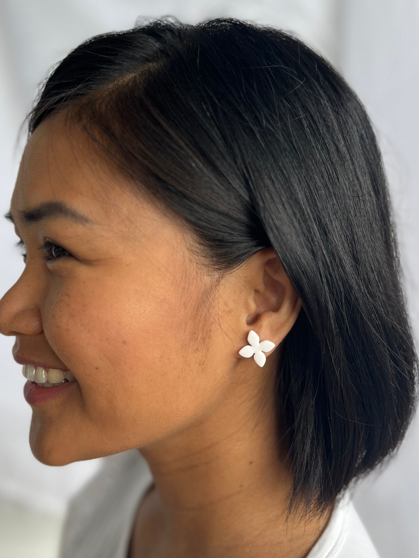 Green, four petalled flower stud earring on models ear