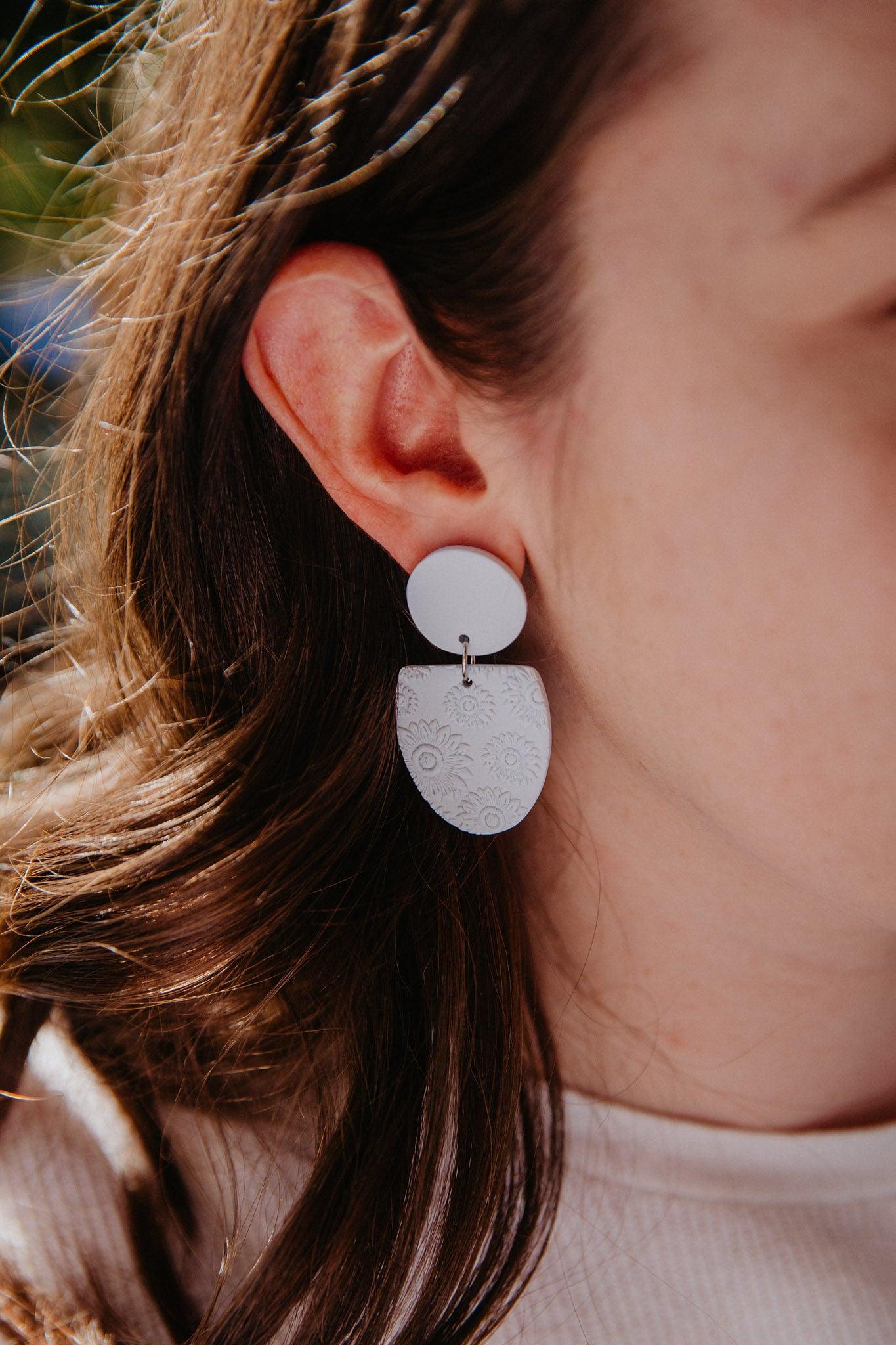 blue oval earrings with daisy print on model