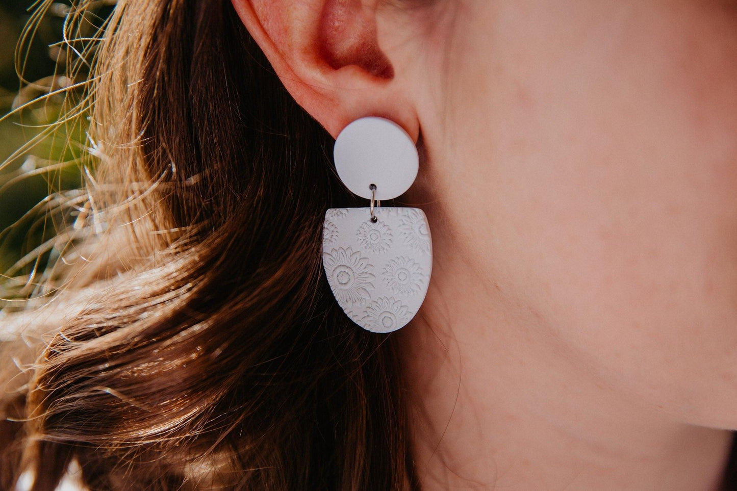 close up of blue oval earrings with flower print worn on a model