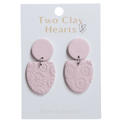 A pair of pink half oval earrings with a flower print on the dangle part