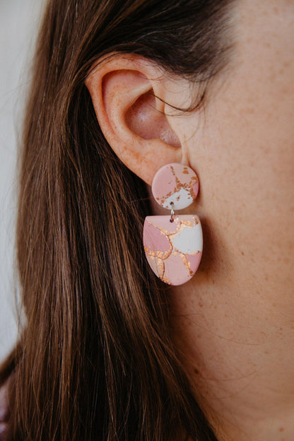 Orange and maroon patterned, half oval dangle earrings worn on models ear