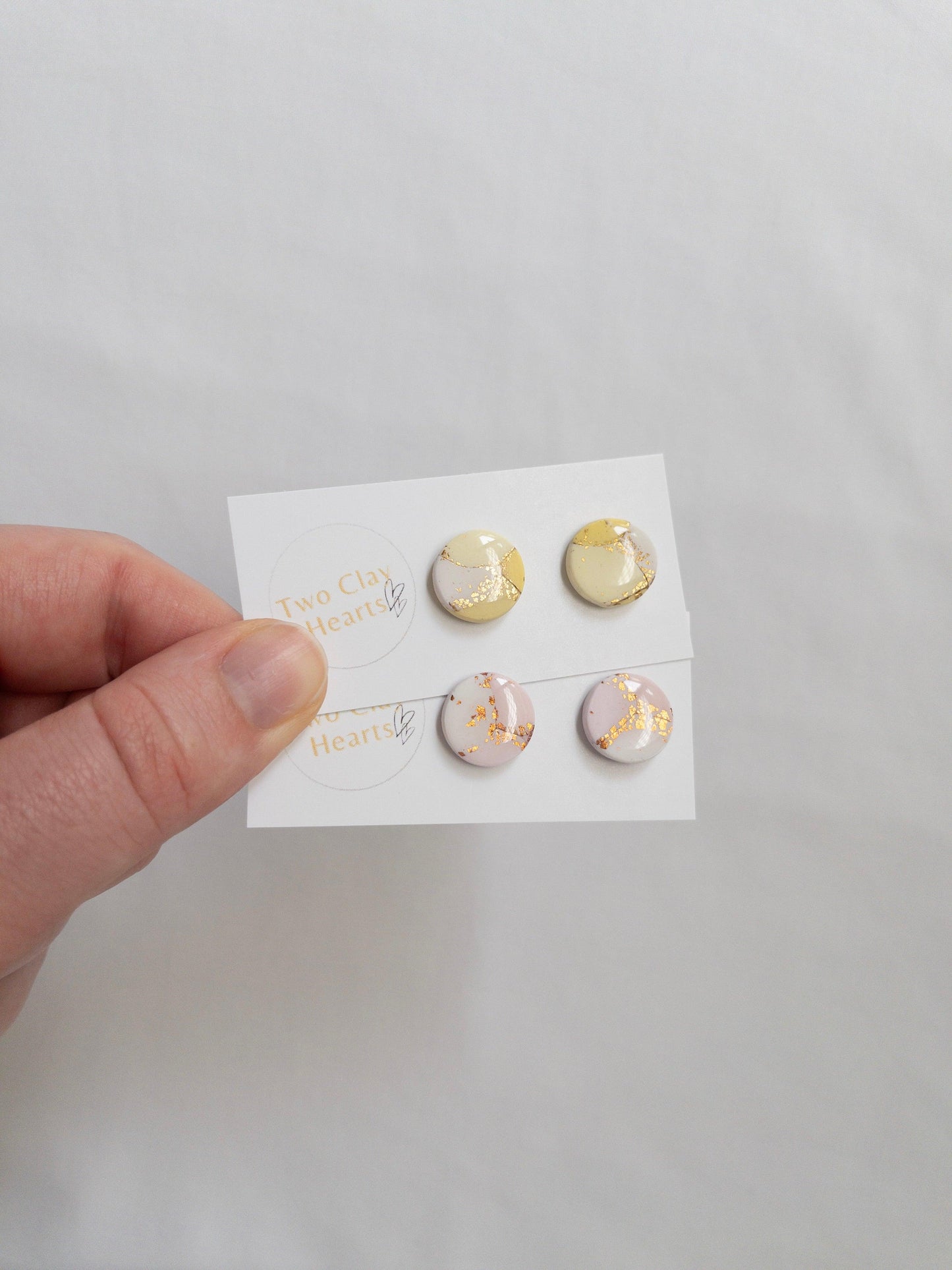 Pastel and gold circle shaped stud earrings on white backing card