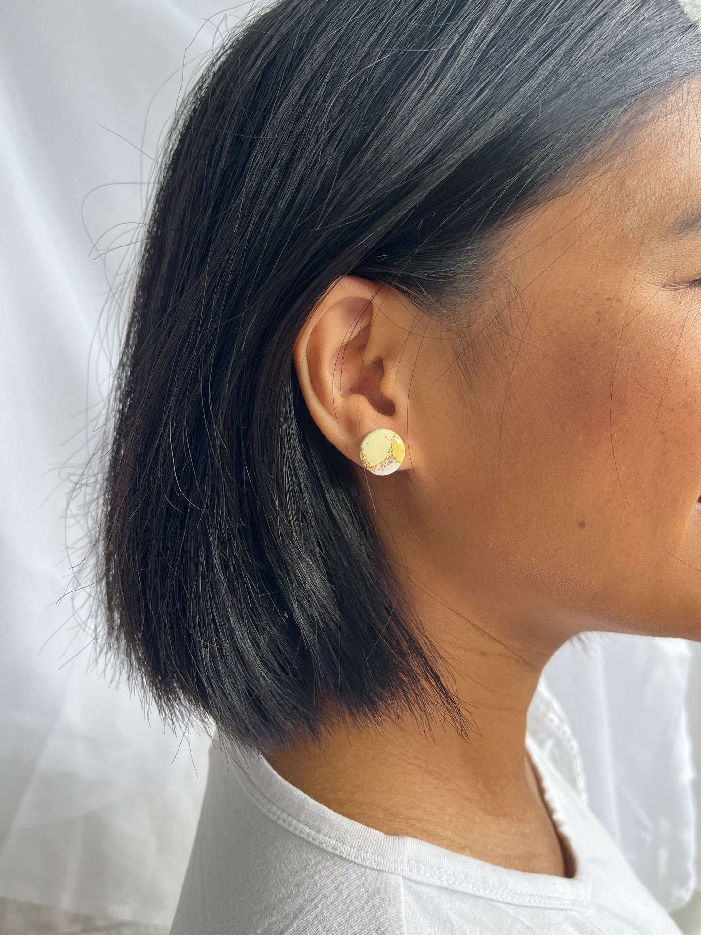 Pastel and gold circle shaped stud earrings on model