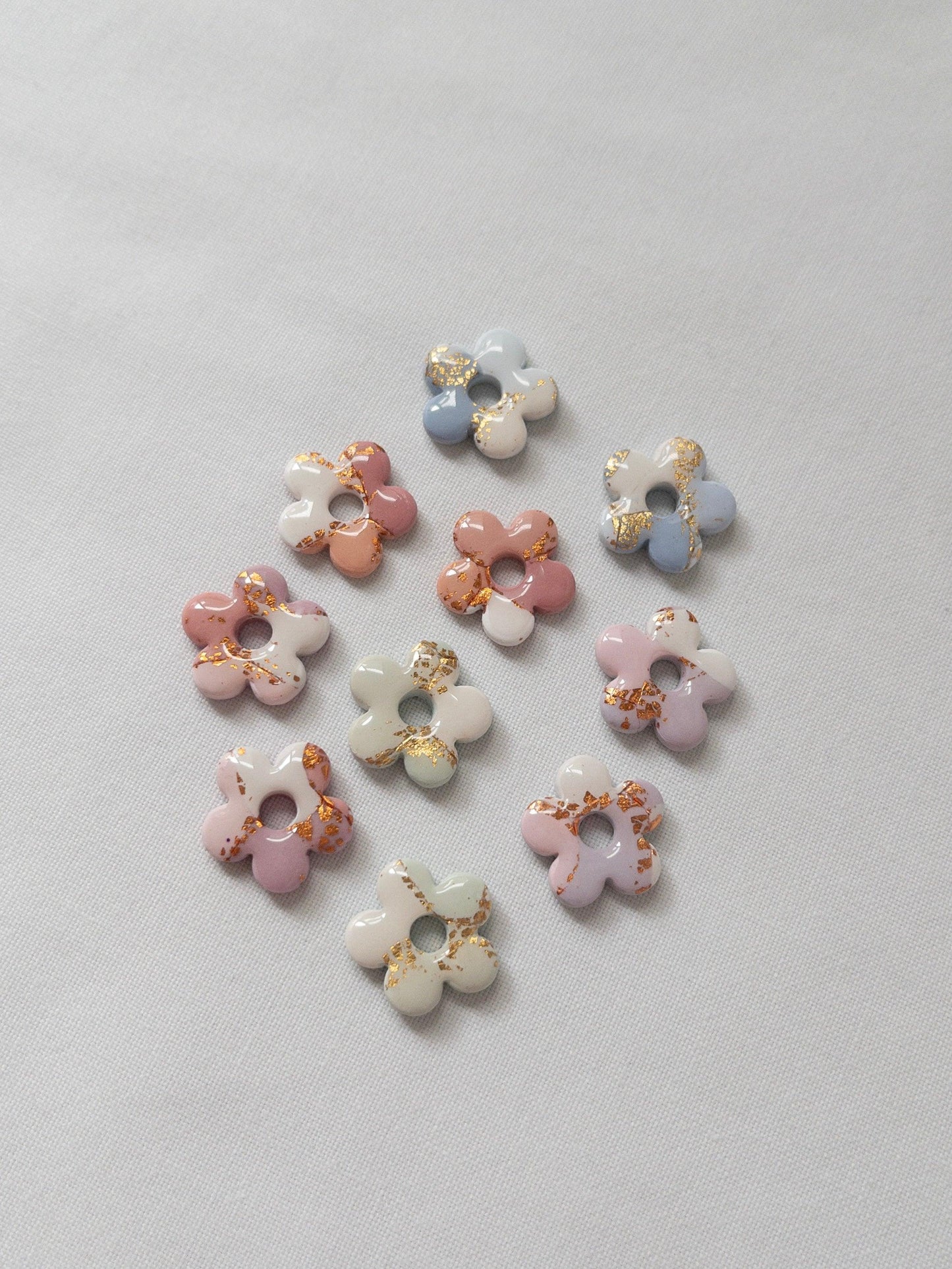 Shiny pastel flower stud earrings on white backdrop