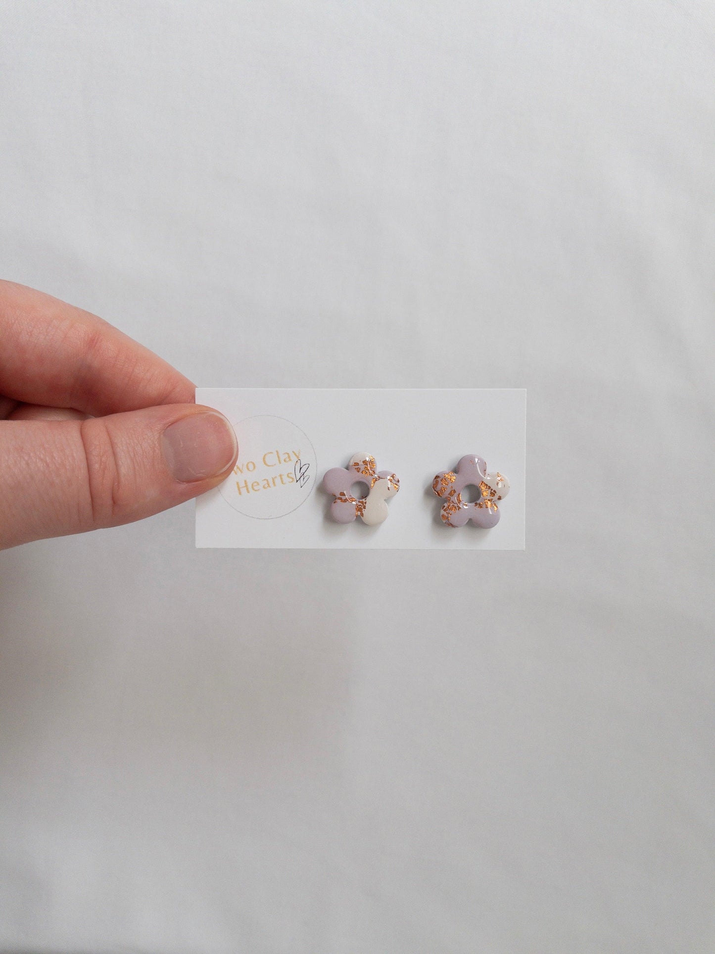 Purple and rose gold flower stud earrings on white backing card