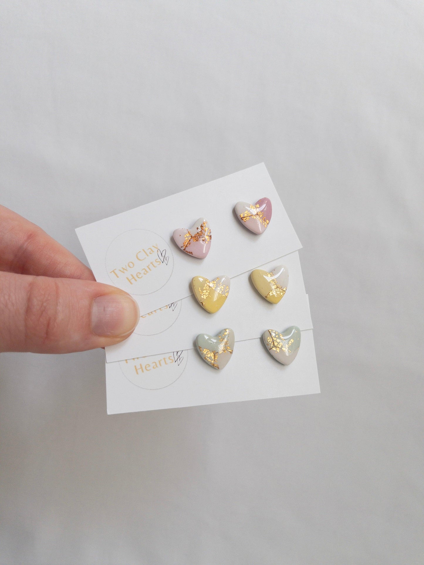 Pastel and gold heart shaped stud earrings on white backing card