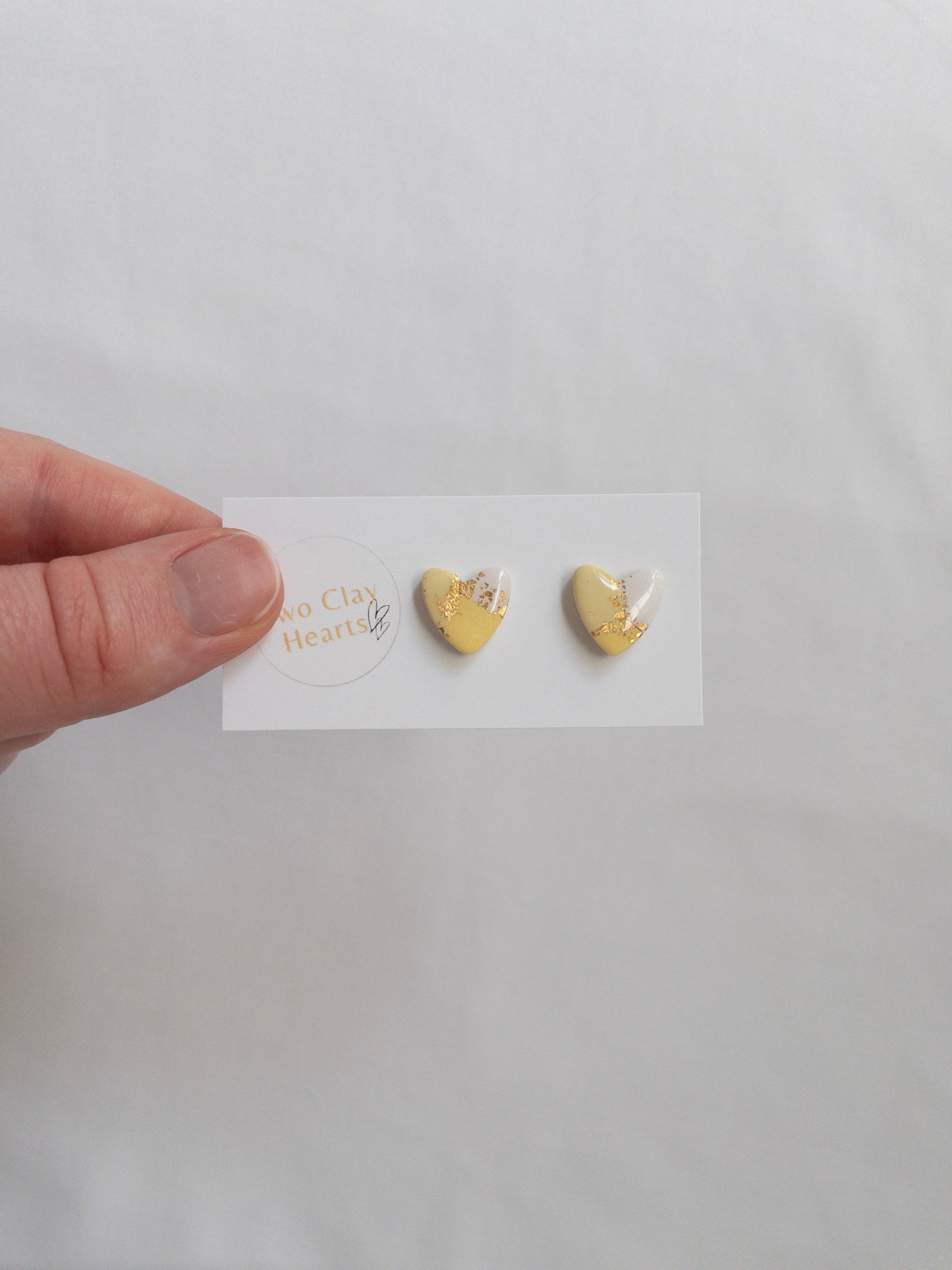 Yellow and gold heart shaped stud earrings on white backing card