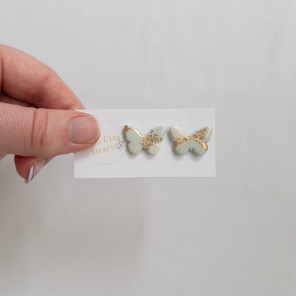 Pastel green and gold butterfly stud earrings on white backing card