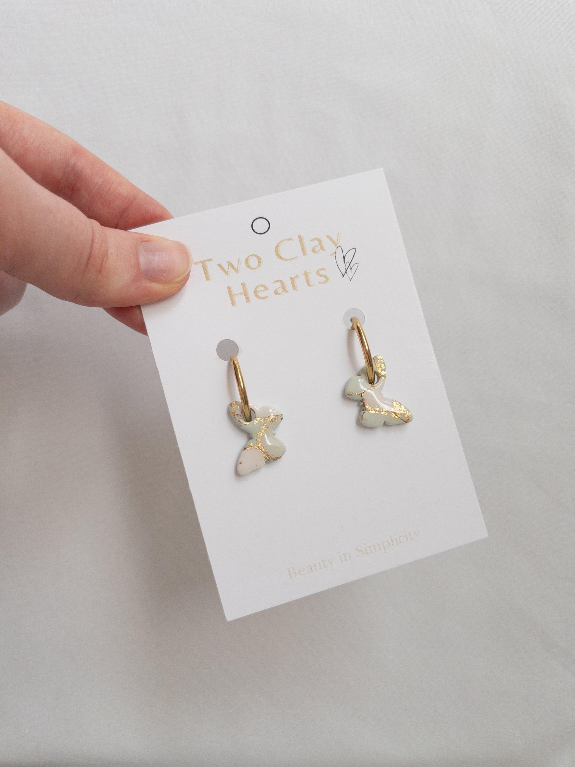 Shiny mint green and gold hoop earrings on white backing card