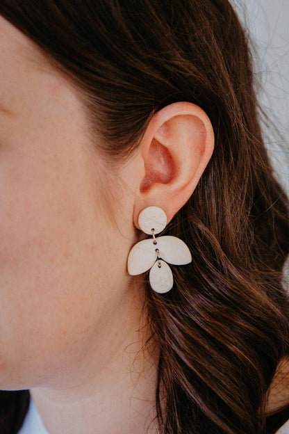 Simple cream firefly shaped earring on models ears