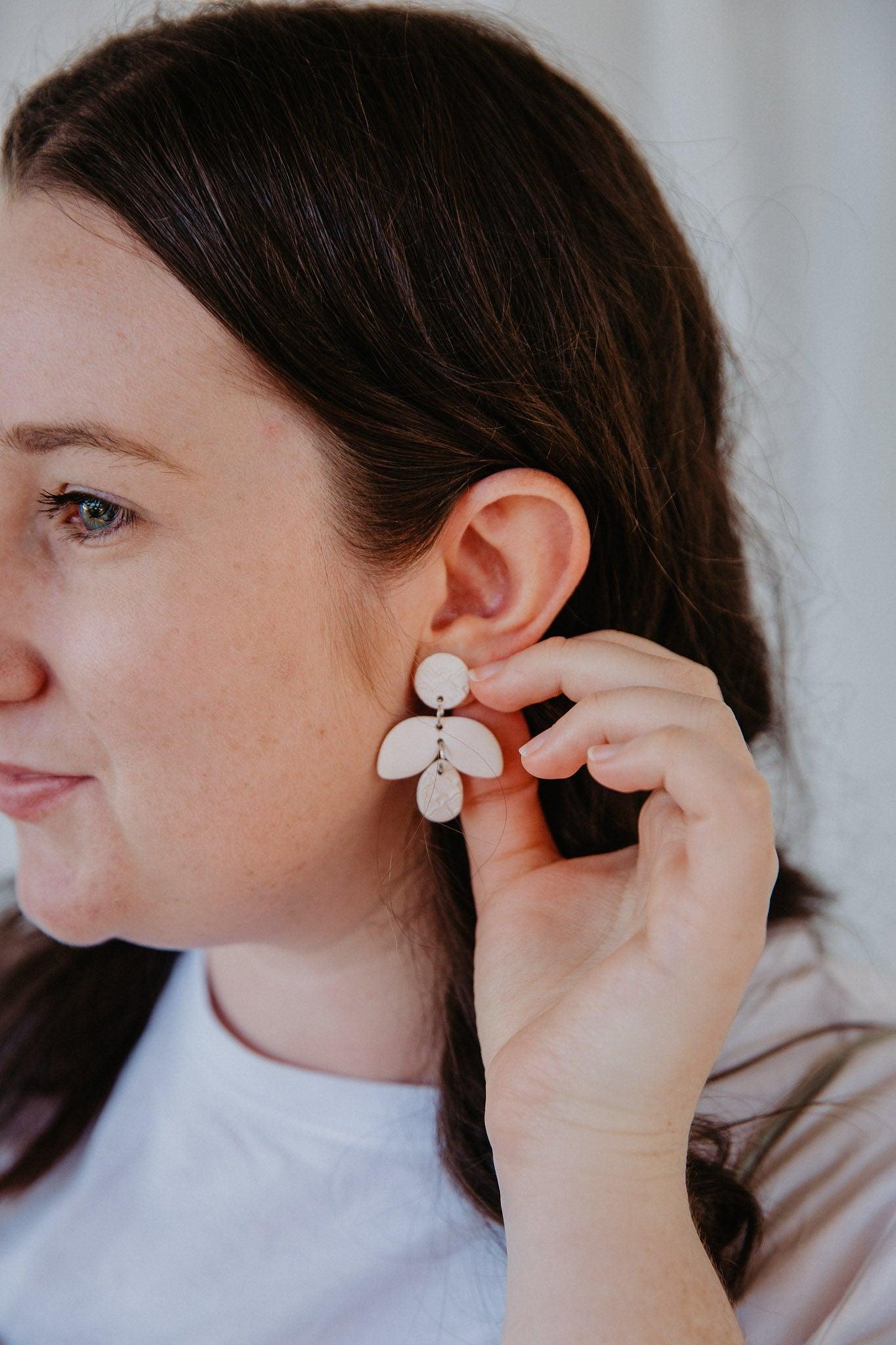 Simple cream firefly shaped earring on models ears