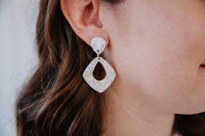 Diamond shaped, white lace dangle earring worn on model