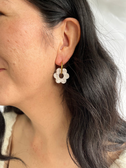 Close up of large white lace flower hoop earrings on models ear