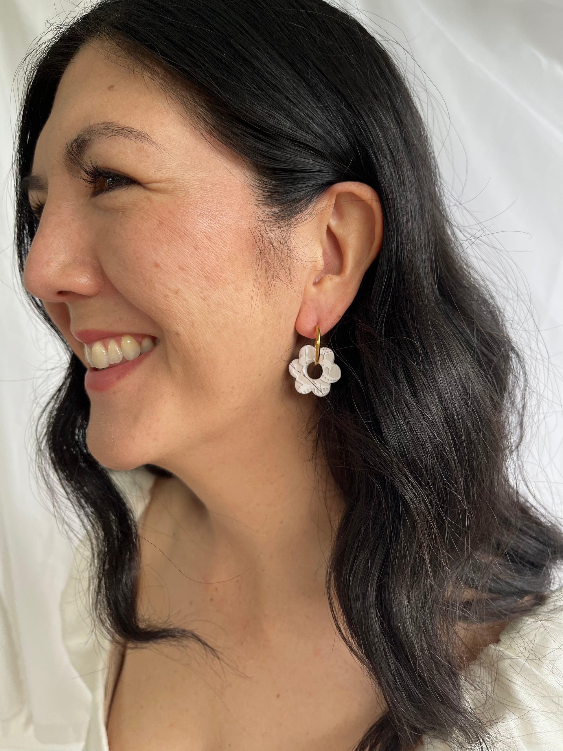 Large white lace flower earrings on models ear