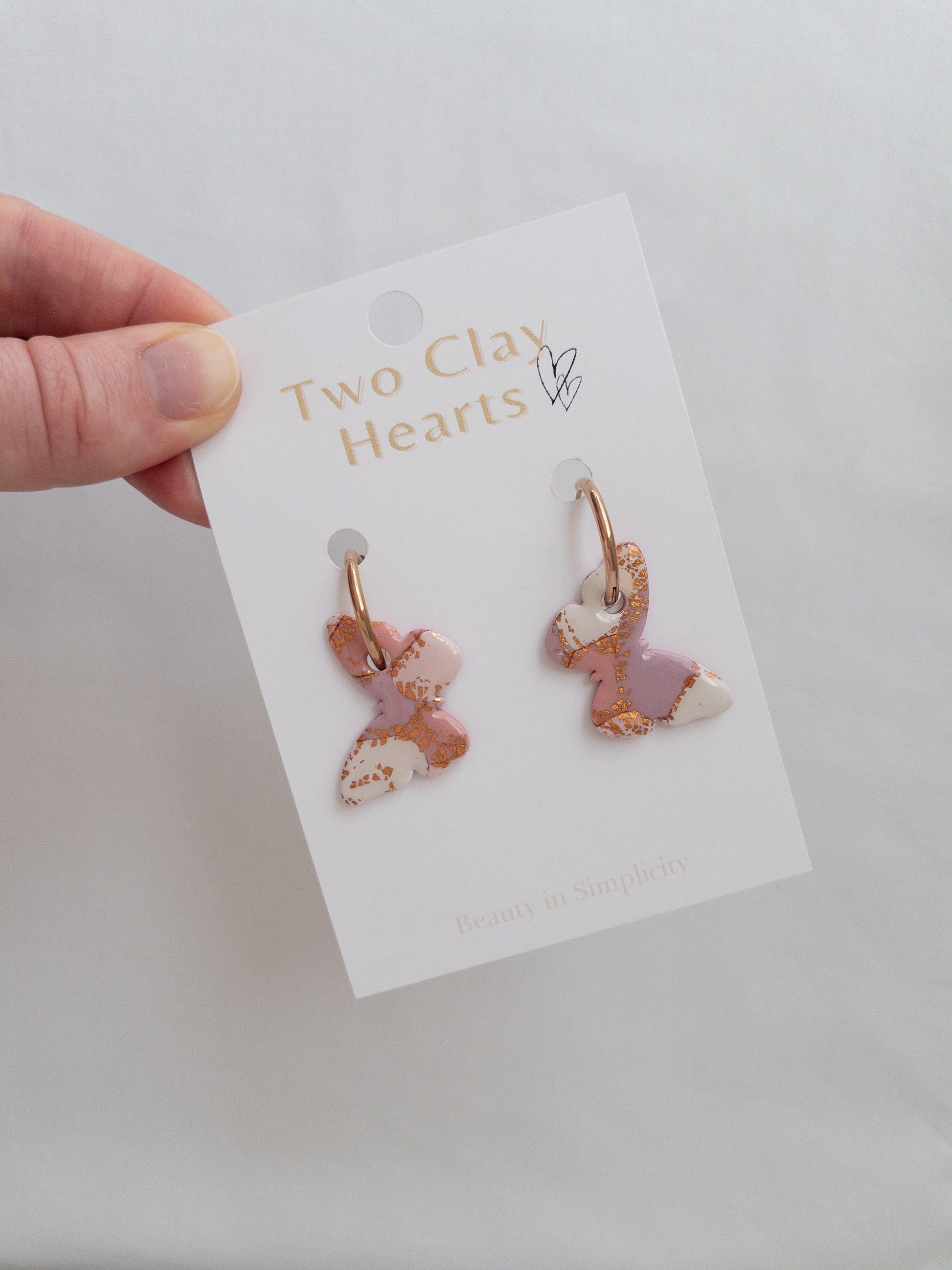 Pink and rose gold large butterfly hoop earrings on backing card