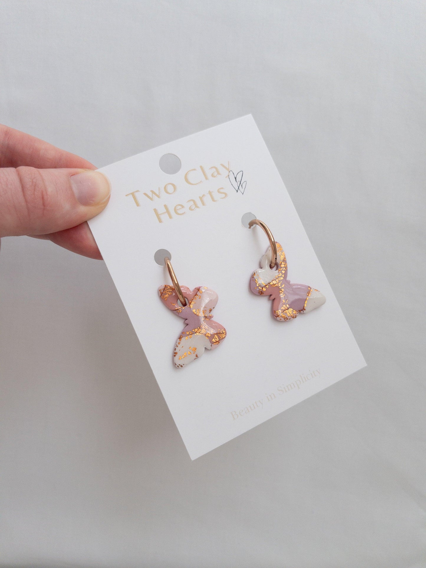 Pink and rose gold large butterfly hoop earrings on backing card