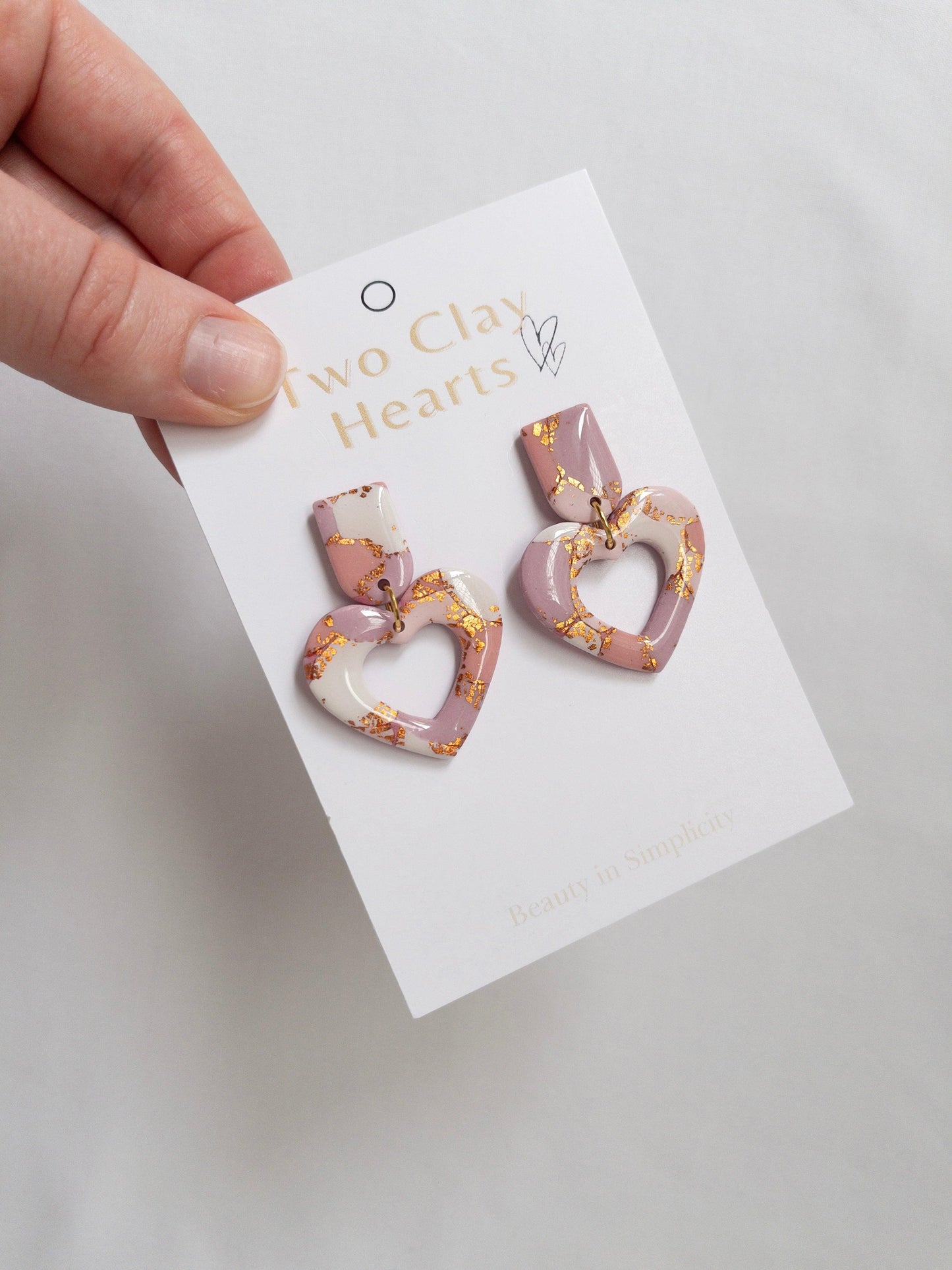 Pink and rose gold heart dangle earrings on white backing card