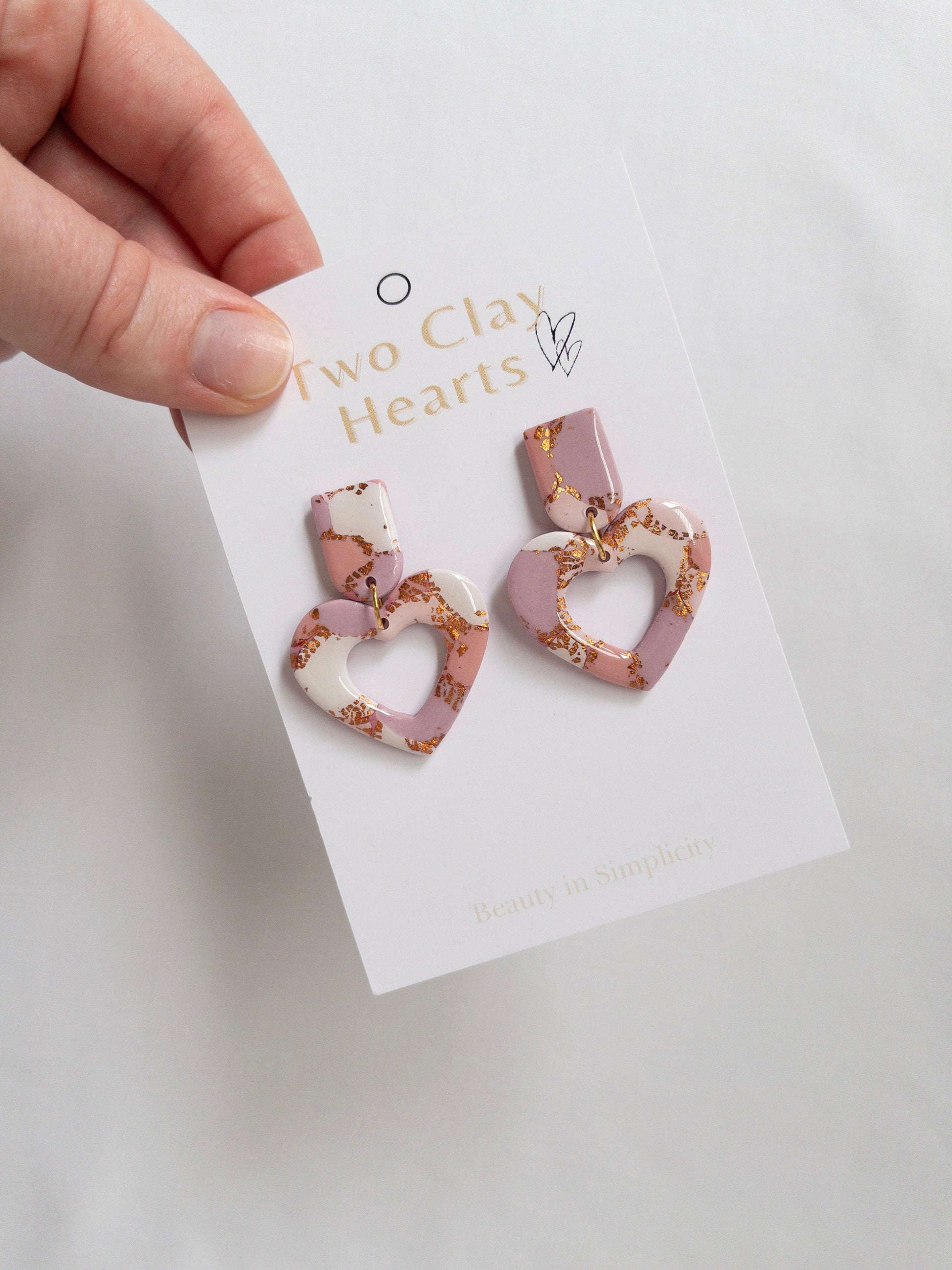 Pink and rose gold heart dangle earrings on white backing card