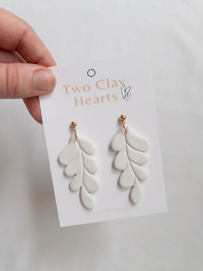 White and gold leaf dangle earrings on white backing card