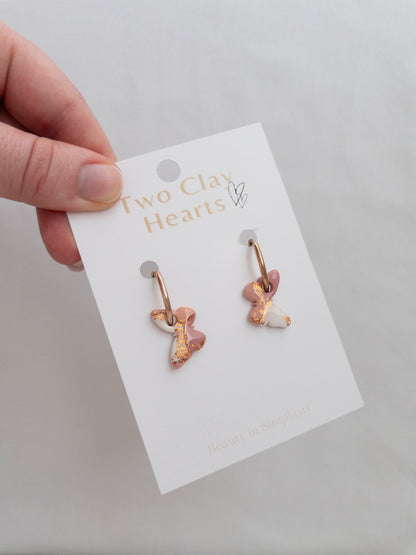 Shiny maroon, orange and rose gold hoop earrings on white backing card