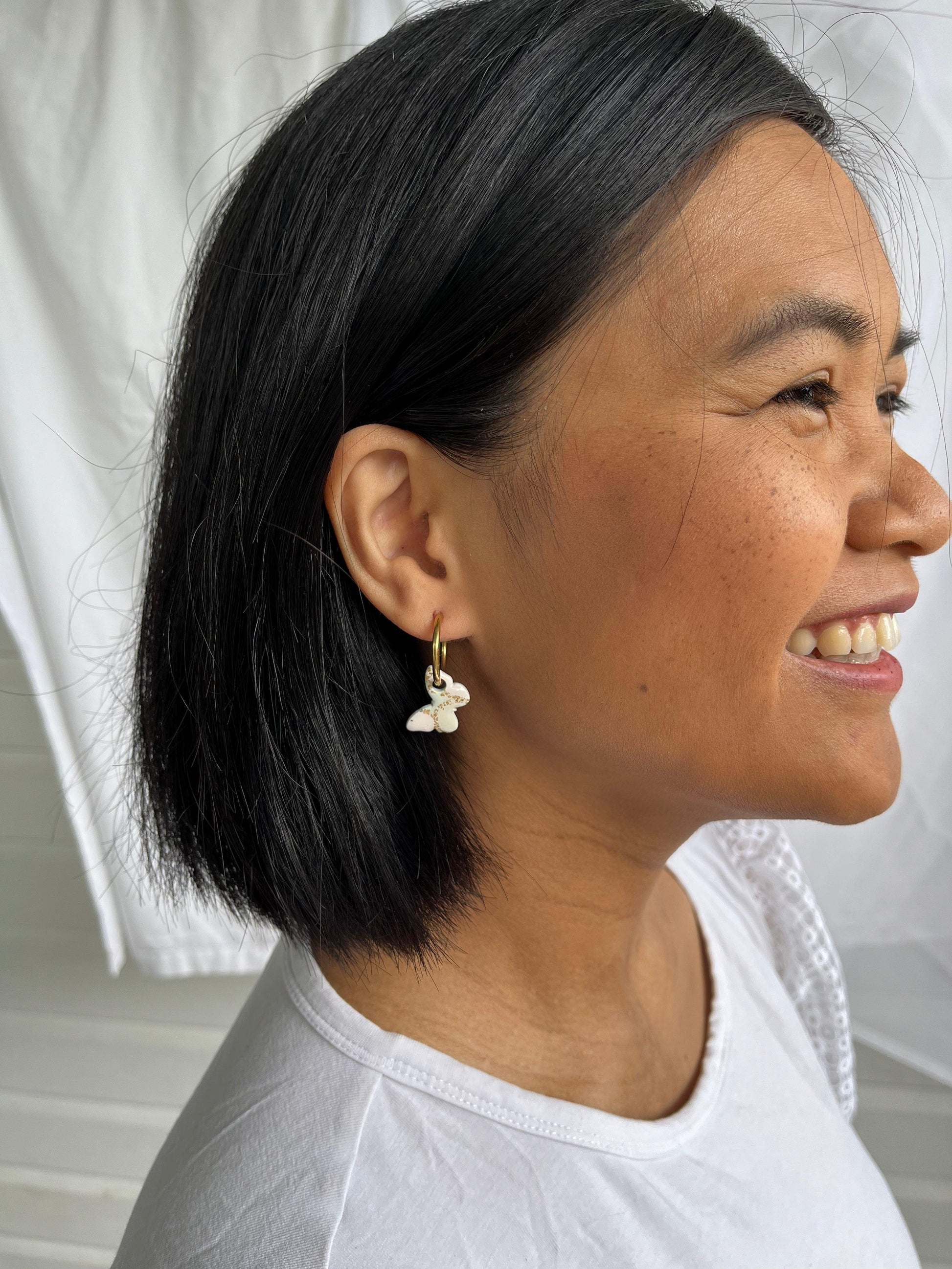 Small pastel green and gold butterfly earrings on models ear