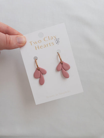 Elegant rose gold and maroon leaf hoop earrings on white backing card