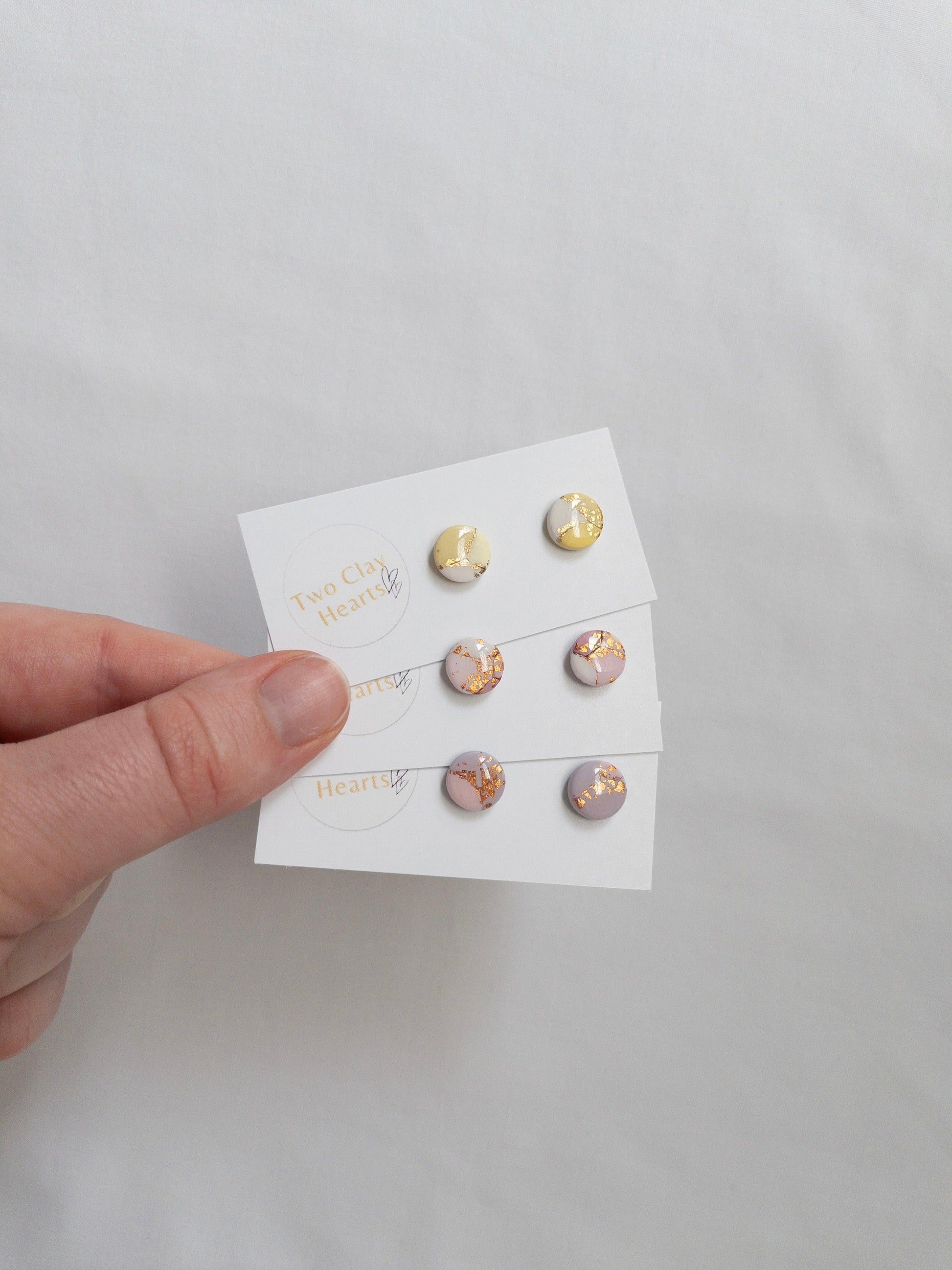 Mini pastel and gold circle stud earrings on white ba